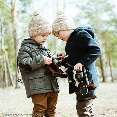 Two young boys in the woods wearing trending anorak jackets and matching beanies