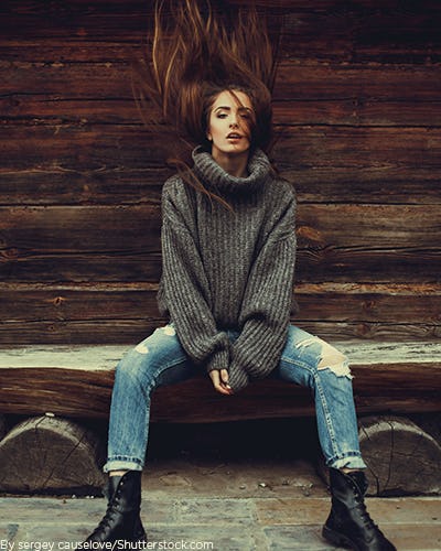 Young woman wearing a thick grey turtleneck sweater with jeans and boots