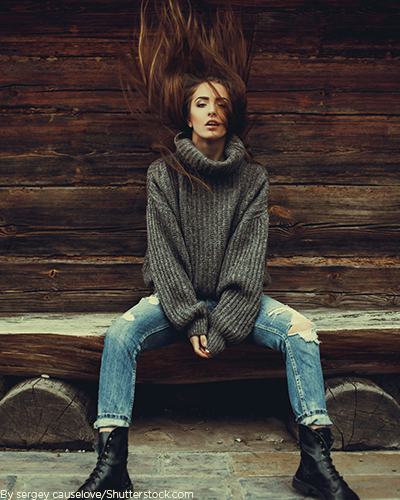 Young woman wearing a thick grey turtleneck sweater with jeans and boots