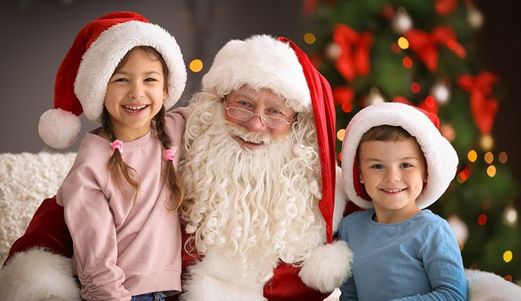 two kids taking photo with santa at santa’s workshop